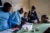 A group of African health workers look at a document laid out in front of them.