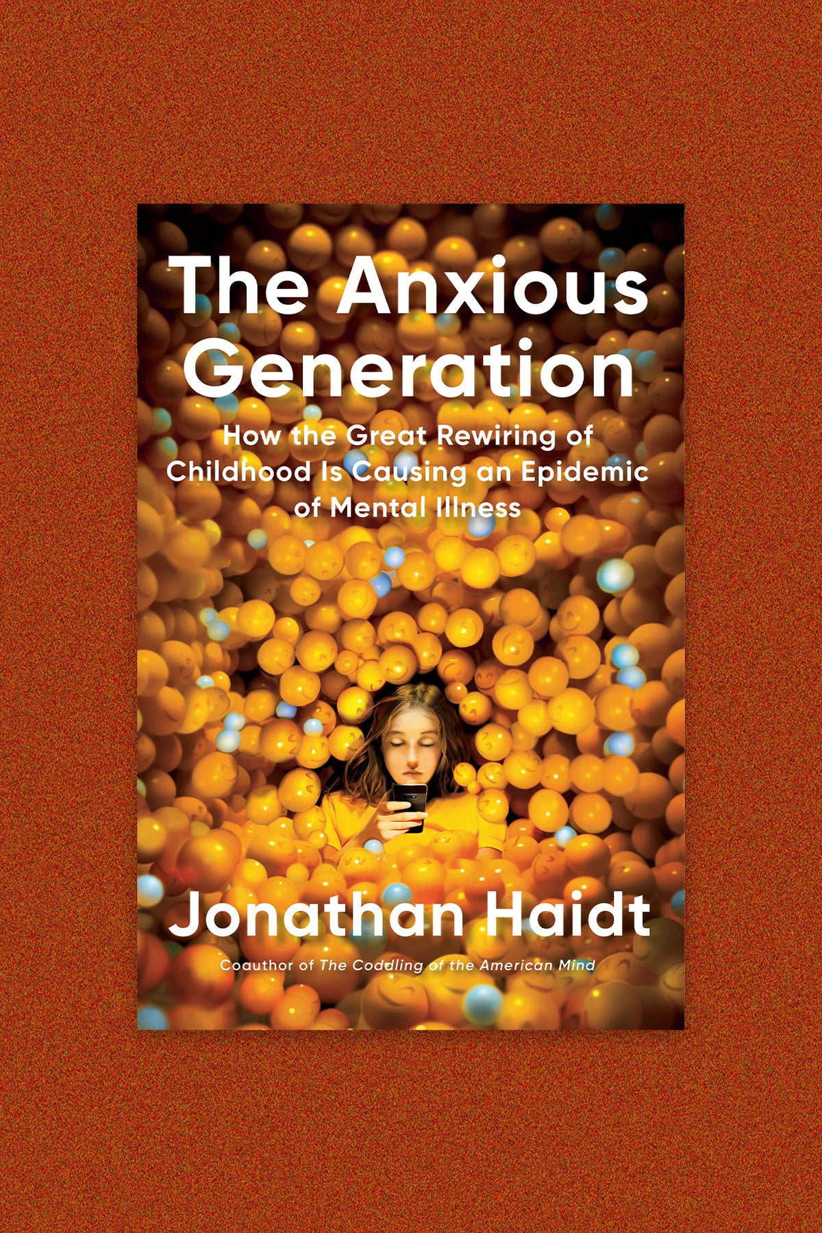 Book cover for “The Anxious Generation: How the great rewiring of childhood is causing an epidemic of mental illness”: Illustration of a young girl on her phone surrounded by 3D smiling emoji balls. Book cover is on an orange-speckled background.