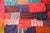 Pieces of colorful square fabric tile a surface. Hand written messaged are stitched in different colored threads.