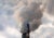 Two smoke stacks emit steam into a cloudy sky.