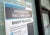 A blue, white and gray sign reads “Monkeypox Vaccine Clinic Right To Access”. It it taped to a storefront window. A “DC Health” logo is affixed to an entrance door in the lower right-hand corner of the image.