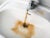 A silver faucet dispenses brown, murky water into a white bathroom sink.