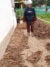 A member of the Cambodia Mine Action Center wearing gear stands next to a school with many unexploded ordinances dug up in rows.