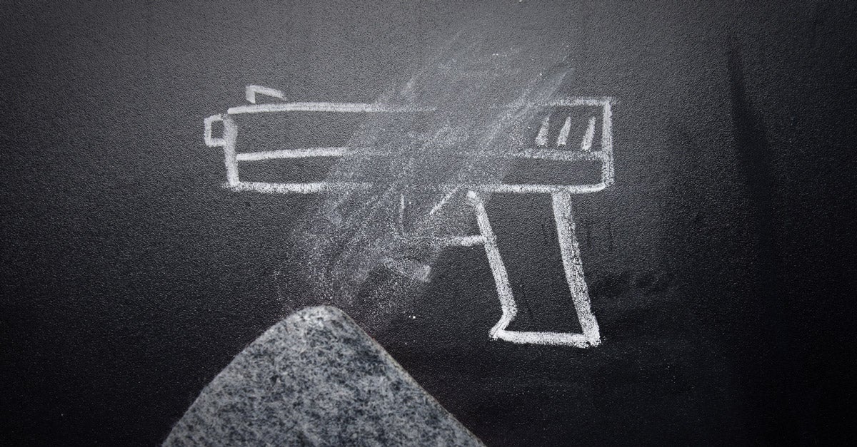 A chalk-drawn handgun being erased on a black chalkboard