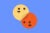 Yellow happiness and orange anger emoticons on a blue background.