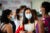 Three femaled, masked students converse.