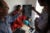 Paul Farmer holds and looks at an X-ray with a fellow clinician in Nepal, 2012. A Nepalese female wearing a red dress sits on a hospital bed next to a laying child wearing a teal shirt with a tube in his nose.