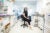 Minmin Yen, seated and wearing a black short-sleeved jumpsuit, sits in a black lab chair in the middle of her white lab at PhagePro.