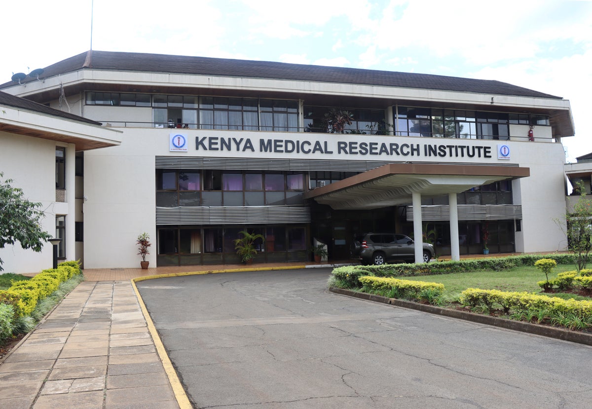 Exterior of a two story white stucco building with the words "Kenyan Medical Research Institute" enscribed.