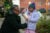 A mother zips up a child's coat at an outdoor Christmas market.The child eats popcorn from a red and white bag.