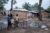 Three African children play outside near housing shanties in central Africa.