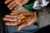 A dark hand holds four orange pills